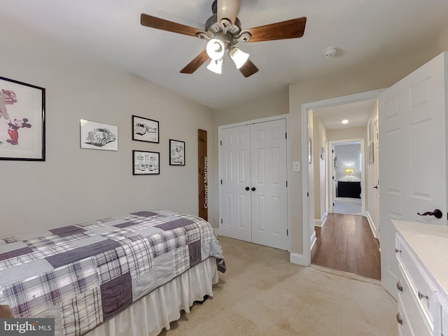 bedroom featuring a closet, light carpet, ceiling fan, and baseboards