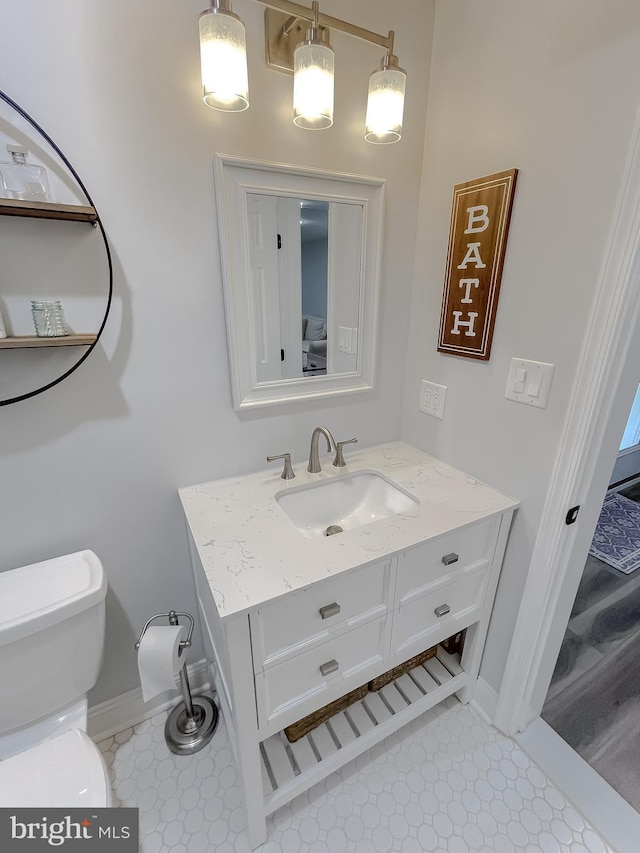 bathroom featuring vanity, toilet, and baseboards