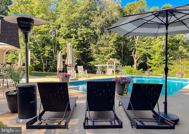 outdoor pool featuring a patio and a playground