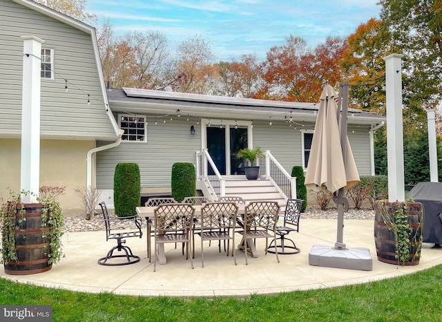 rear view of property with outdoor dining space, roof mounted solar panels, and a patio area