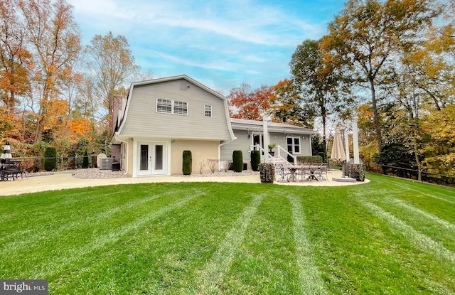 rear view of property with a yard, a patio area, fence, and a gambrel roof