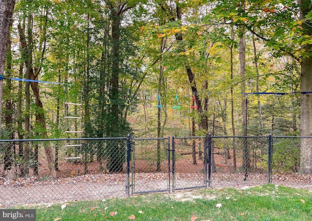 view of yard with a gate, fence, and a wooded view