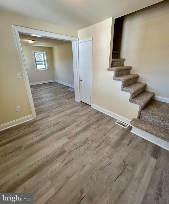 basement featuring visible vents, stairway, baseboards, and wood finished floors