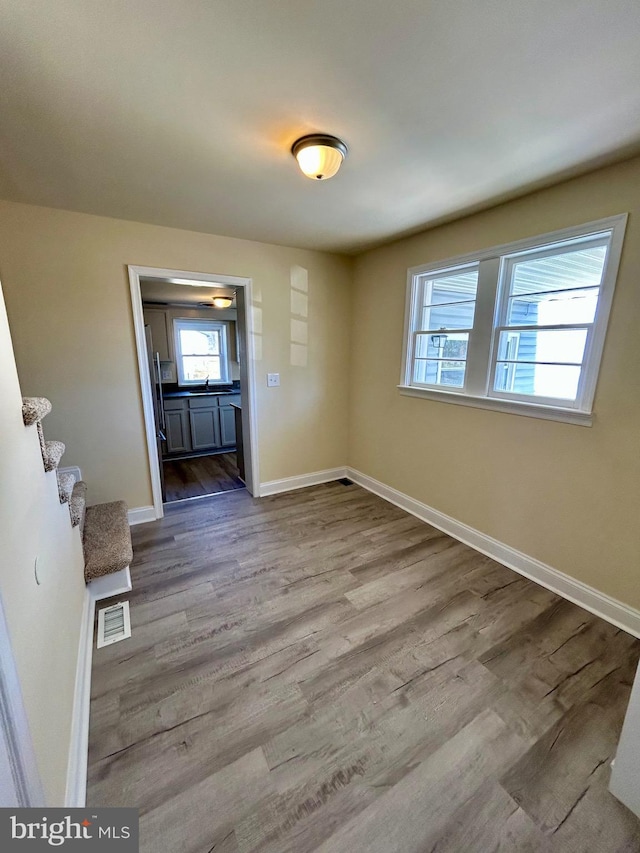 unfurnished dining area with wood finished floors, visible vents, and baseboards