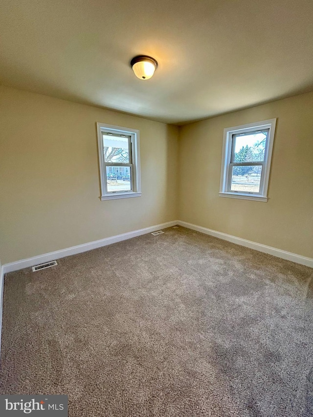 spare room with baseboards, plenty of natural light, visible vents, and carpet flooring