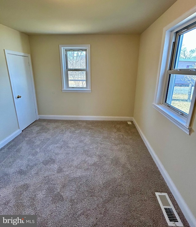 unfurnished bedroom with carpet, visible vents, baseboards, and multiple windows