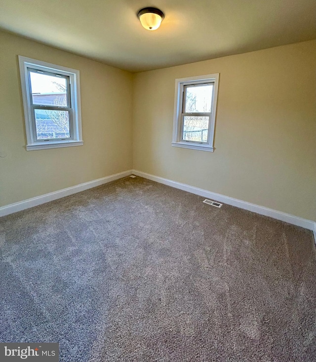 carpeted spare room featuring baseboards and visible vents