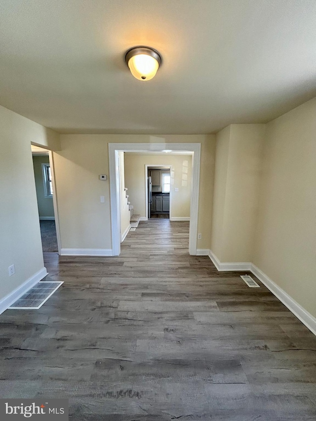 unfurnished room with wood finished floors, visible vents, and baseboards