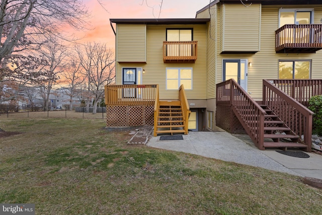 back of property at dusk featuring a lawn and fence