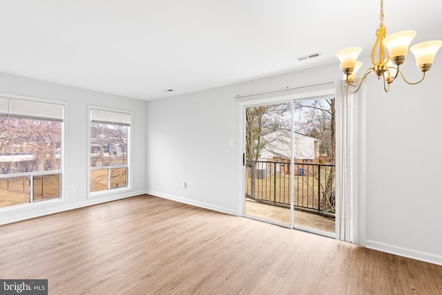 interior space featuring baseboards, visible vents, an inviting chandelier, and wood finished floors