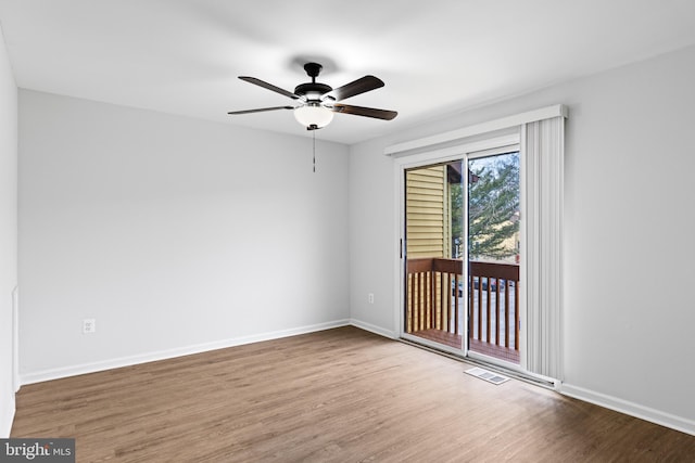 spare room featuring a ceiling fan, wood finished floors, visible vents, and baseboards