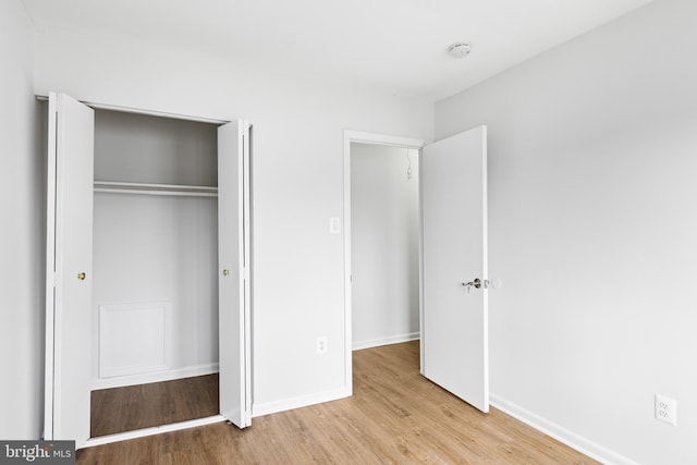 unfurnished bedroom featuring a closet, baseboards, and wood finished floors