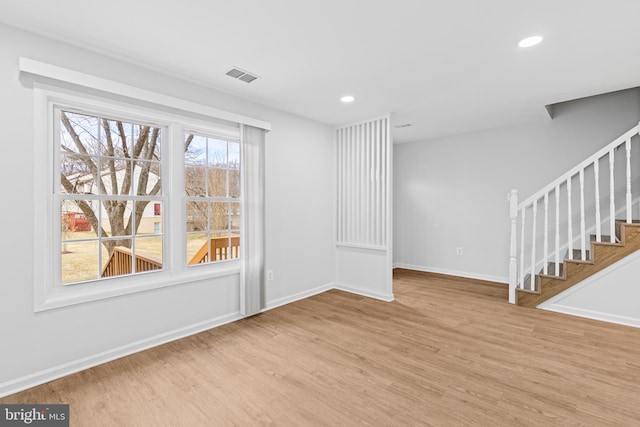 empty room with recessed lighting, visible vents, wood finished floors, baseboards, and stairs