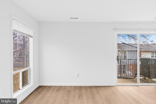 empty room featuring wood finished floors, visible vents, and baseboards