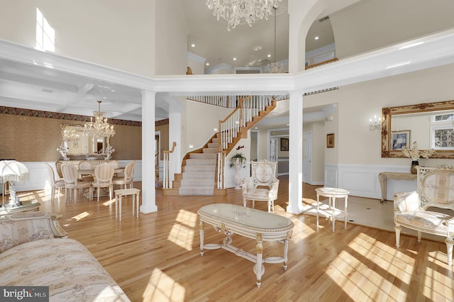 living area with a chandelier, a wainscoted wall, stairs, and wood finished floors