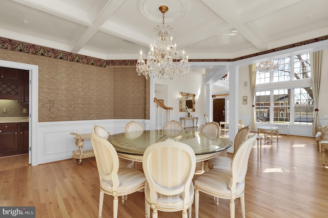 dining space featuring a chandelier, beam ceiling, wainscoting, light wood-style flooring, and coffered ceiling