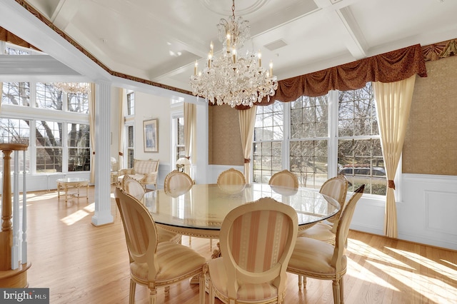 dining room featuring coffered ceiling, light wood-style flooring, wainscoting, beamed ceiling, and a chandelier