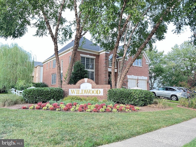 community sign with a lawn and an attached garage