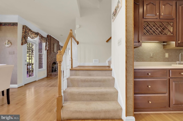 staircase with hardwood / wood-style flooring, a fireplace, visible vents, and baseboards