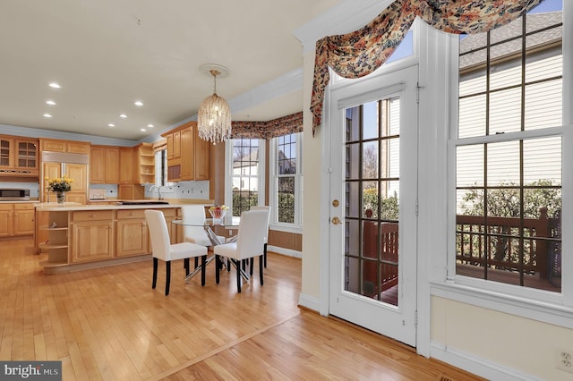 dining space with a notable chandelier, recessed lighting, crown molding, and light wood-style floors