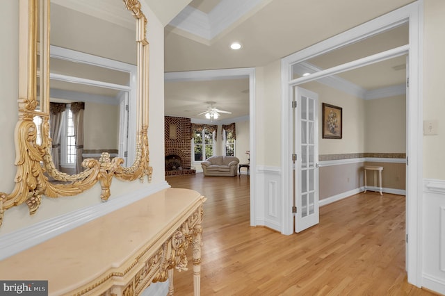 hall featuring recessed lighting, a wainscoted wall, crown molding, and light wood finished floors