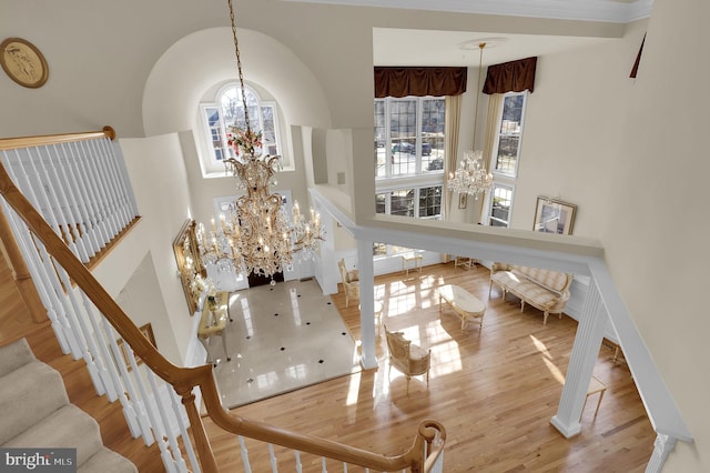 entryway with plenty of natural light, a towering ceiling, an inviting chandelier, and wood finished floors