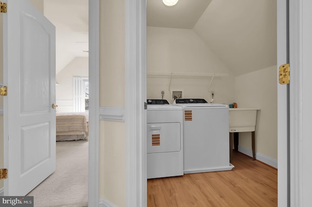 clothes washing area with washer and dryer, light wood-style floors, and laundry area