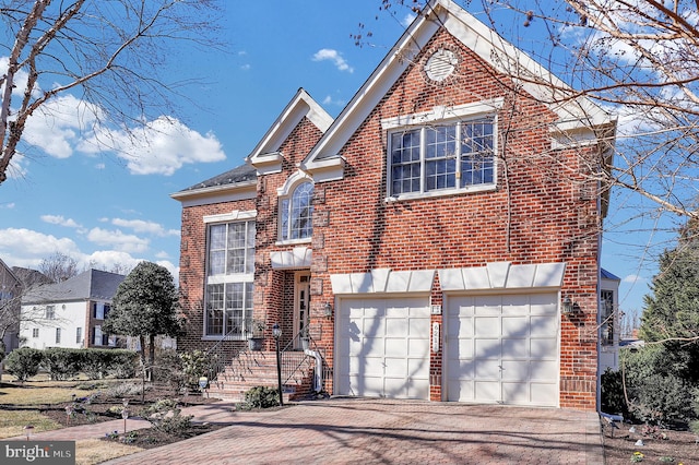 traditional-style home featuring brick siding, an attached garage, and driveway