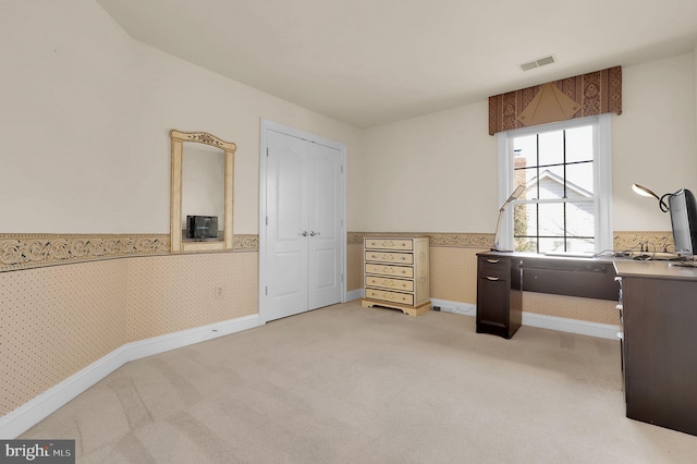 office featuring baseboards, visible vents, wallpapered walls, wainscoting, and light carpet