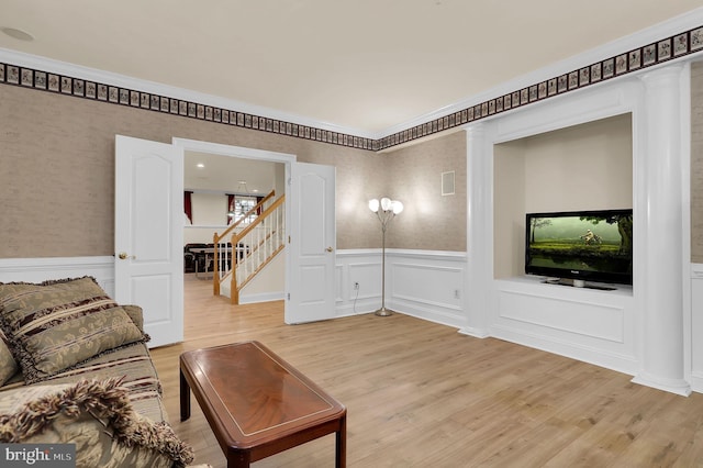 living room featuring stairway, light wood-style floors, and a wainscoted wall