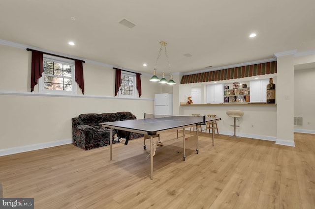 rec room with visible vents, baseboards, light wood-style floors, and ornamental molding