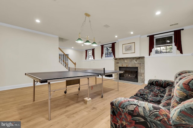 rec room featuring visible vents, crown molding, a stone fireplace, recessed lighting, and light wood-style floors