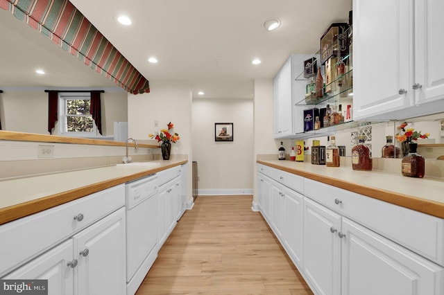 kitchen with light wood finished floors, a sink, dishwasher, white cabinets, and open shelves