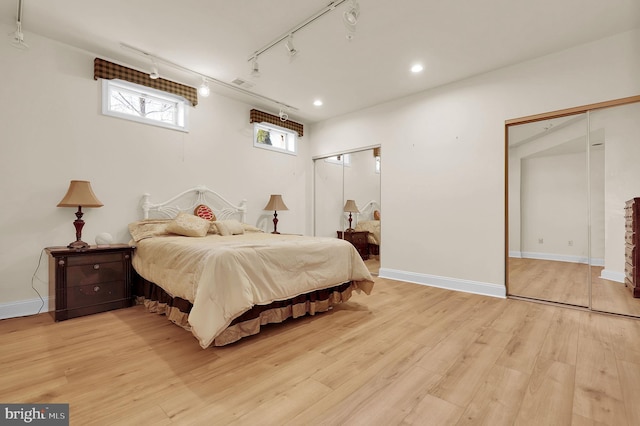 bedroom with visible vents, light wood-style flooring, baseboards, and multiple closets