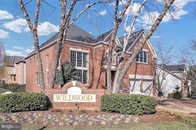 community sign with concrete driveway and a garage