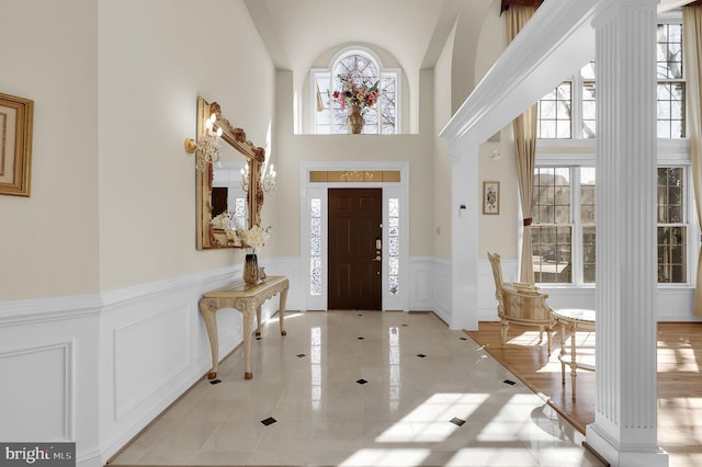 entryway with decorative columns, a wainscoted wall, and a decorative wall