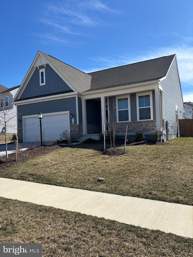 view of front of property featuring board and batten siding, a garage, stone siding, driveway, and a front lawn