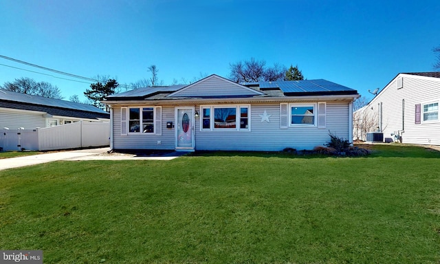 view of front of house featuring central air condition unit, fence, a front lawn, and solar panels