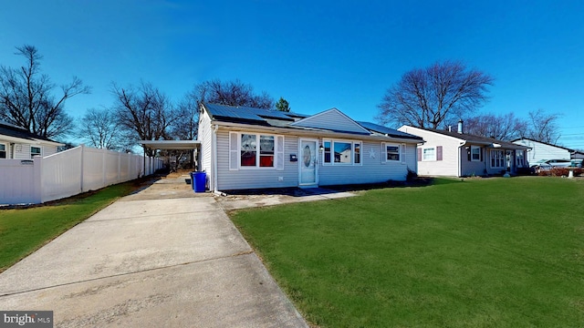 view of front of home featuring solar panels, concrete driveway, fence, a carport, and a front yard