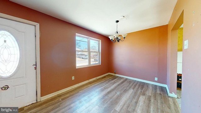 entrance foyer with a notable chandelier, wood finished floors, and baseboards