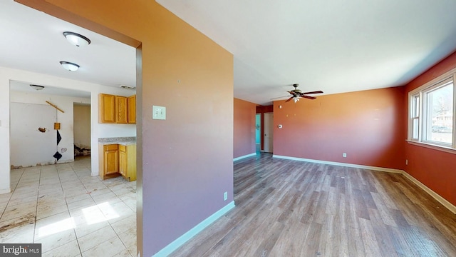 spare room with light wood-style flooring, a ceiling fan, and baseboards