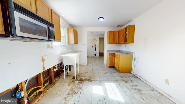 kitchen with brown cabinets, light countertops, visible vents, and a sink