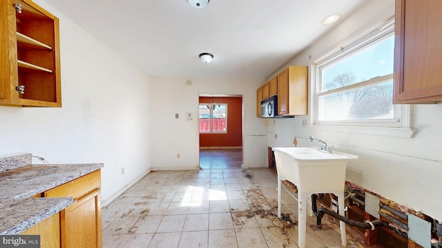 kitchen with brown cabinetry, light countertops, plenty of natural light, and baseboards