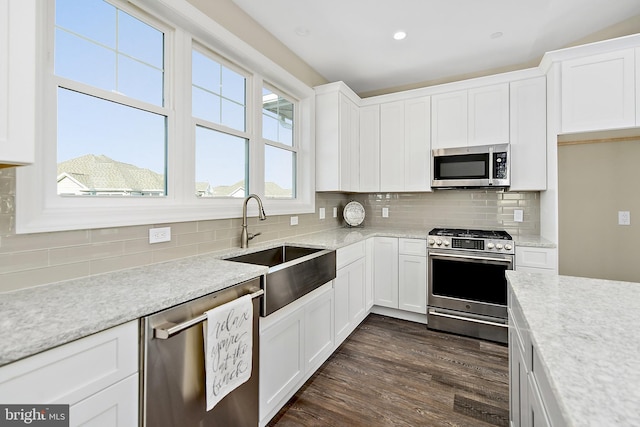 kitchen featuring appliances with stainless steel finishes, a sink, white cabinets, and tasteful backsplash