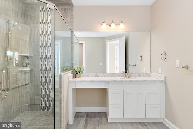 bathroom featuring a stall shower, vanity, and baseboards