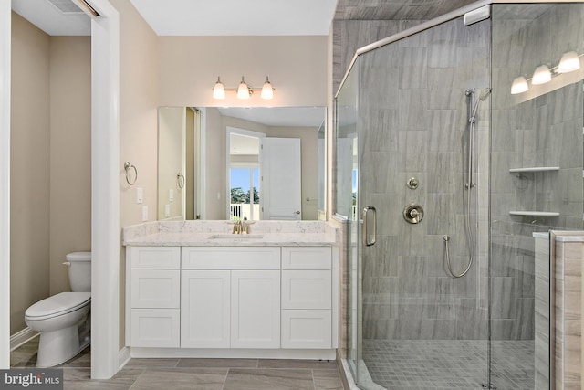 full bath featuring a stall shower, baseboards, vanity, and toilet