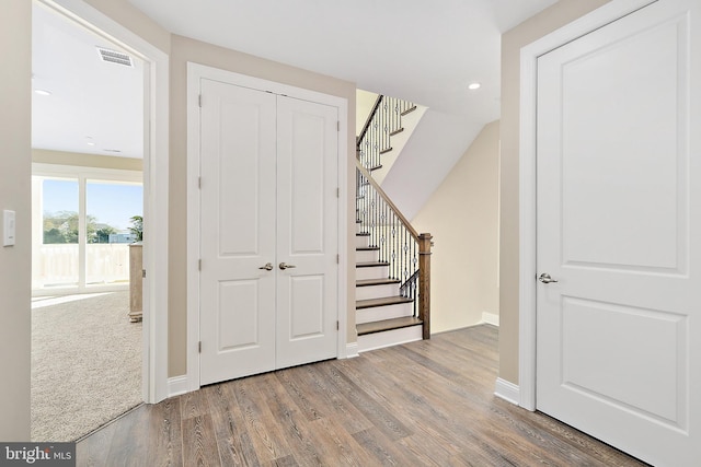 foyer with stairway, baseboards, visible vents, and wood finished floors