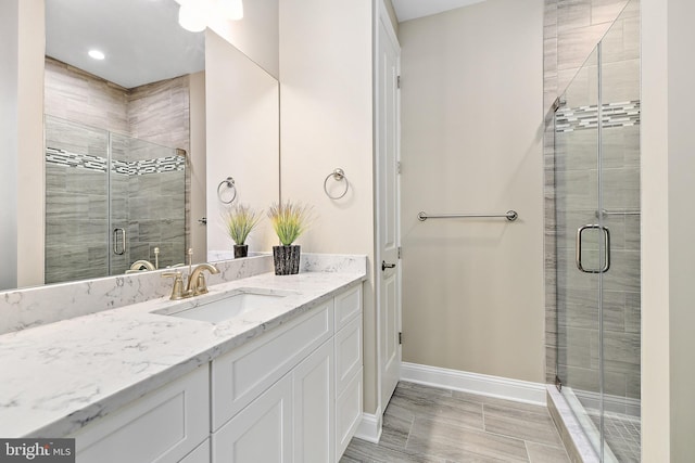 full bath with a shower stall, baseboards, and vanity