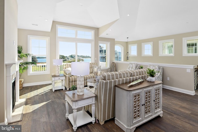 living area with dark wood-style flooring, a fireplace, visible vents, and baseboards