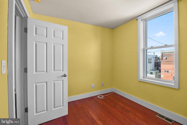 unfurnished bedroom featuring dark wood-style flooring, visible vents, and baseboards